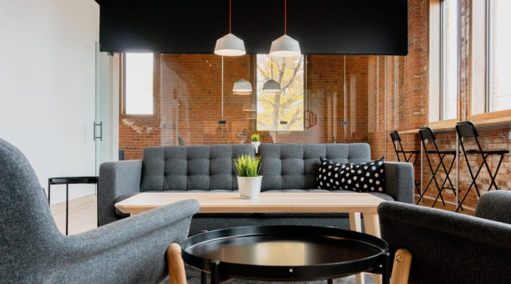 Salon avec canapé gris et deux fauteuils